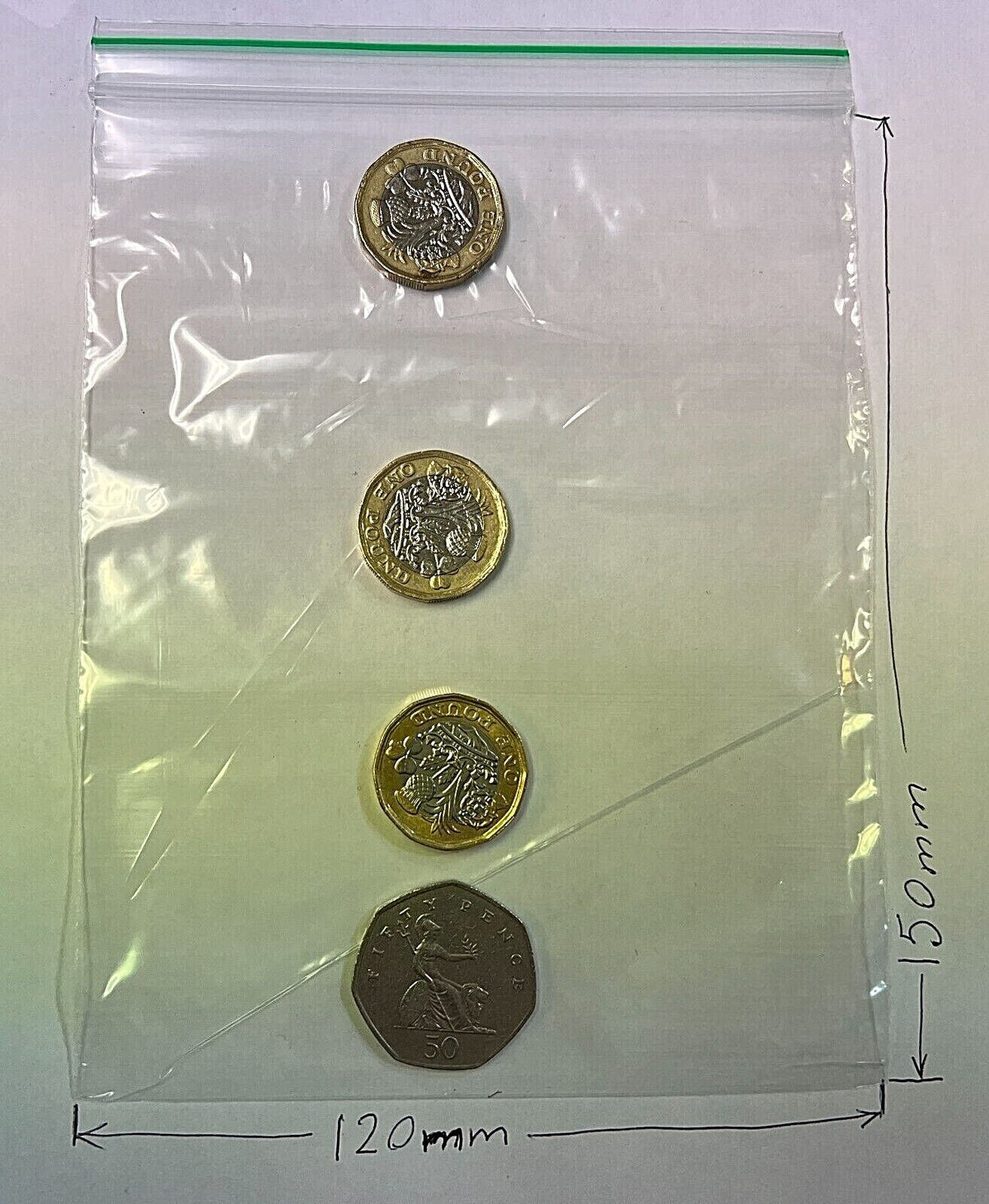 A clear plastic zip-top storage bag with four coins placed inside,  dimension markers indicating 120 mm width and 150 mm height.