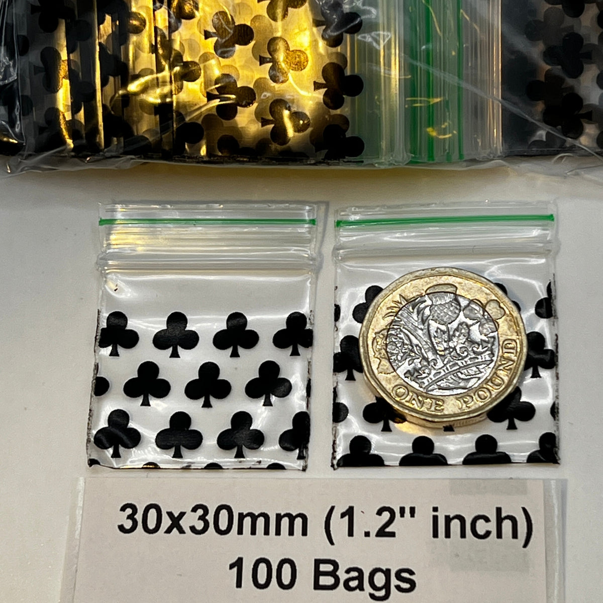 Two clear plastic zip-top bags printed with black club symbols are shown on a white surface, with one bag containing a coin for scale. A label below reads '30x30mm (1.2 inch)