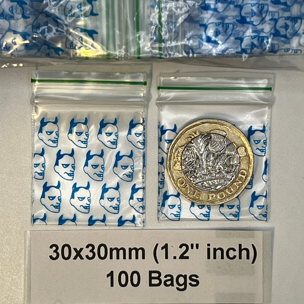 Two blue devil printed baggies.  plastic zip bags  with a £1 coin placed inside one bag for scale. Text at the bottom reads '30x30mm (1. inch)